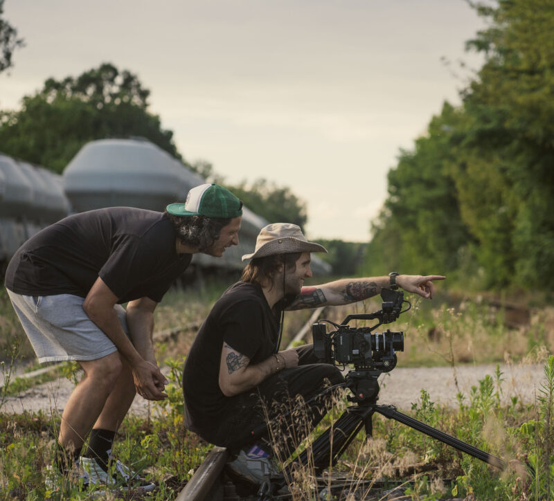 Twórcy filmu reklamowego przy kamerze podczas omawiania ujęcia w plenerze